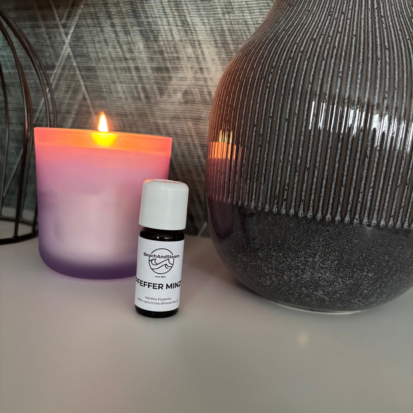 Ätherisches Pfefferminzöl in 10 ml Flasche von BeachAndSteam, zeigt die Flasche mit Minzblättern im Hintergrund