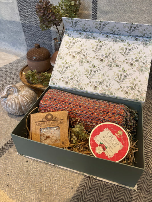 Geschenkbox mit grünem Deckel und Eukalyptus-Innenseite, gefüllt mit einem Hamamtuch, Peelingsalz und Badesalz, dekorativ auf Holzwolle arrangiert.