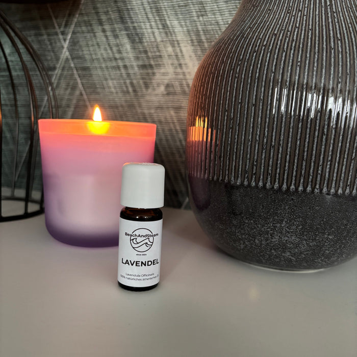 Ätherisches Lavendelöl von BeachAndSteam in einer 10 ml Flasche, mit Lavendelblüten im Hintergrund.