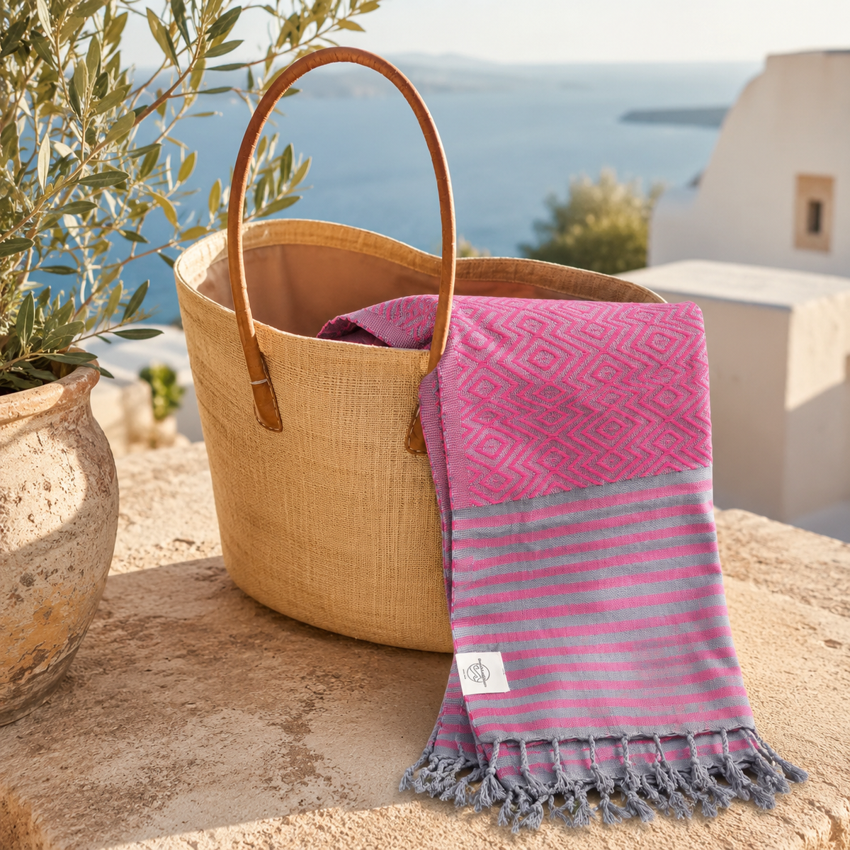 Pinkes Strandtuch MAHINA an einer Strandtasche vor einer weißen Hauswand