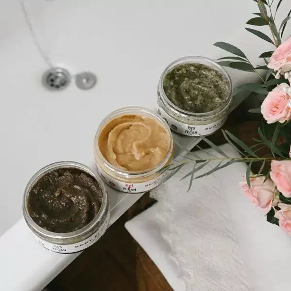Drei VEGAN FOX Körperpeelings Ingwer, Kaffee und Pfefferminze am Badewannenrand